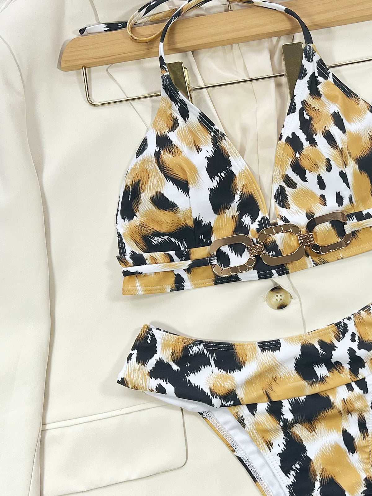 Close-up of black, white and gold printed triangle bikini top with linked waist detail