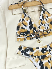 Close-up of black, white and gold printed triangle bikini top with linked waist detail