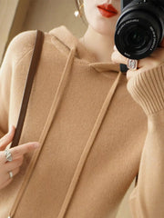 Camel hooded knit sweater shown in a close mirror photo with a shoulder bag.