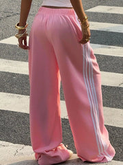 Dark charcoal track pants with white side stripes, front view