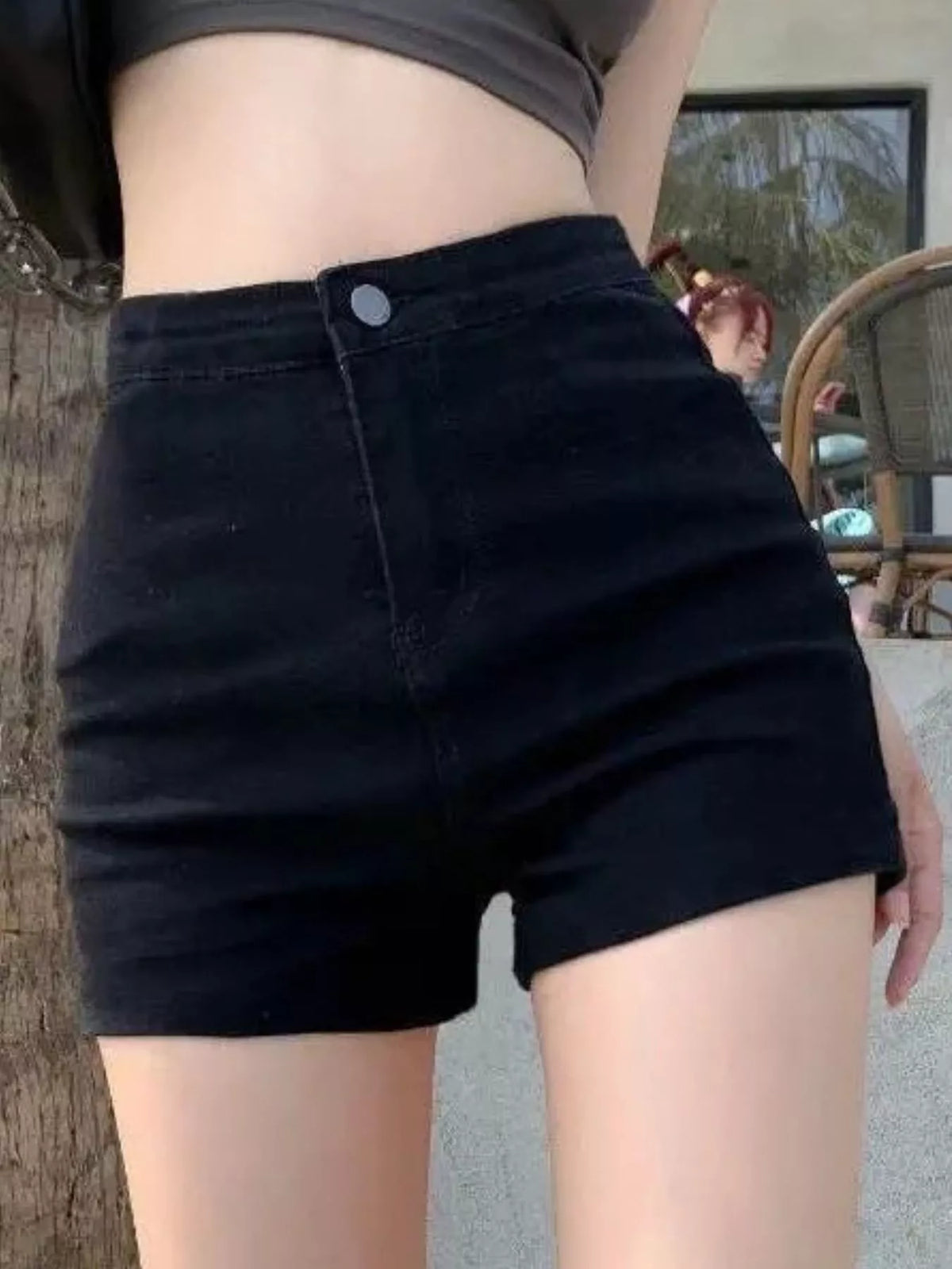 Model wearing black high-waisted denim shorts, front view