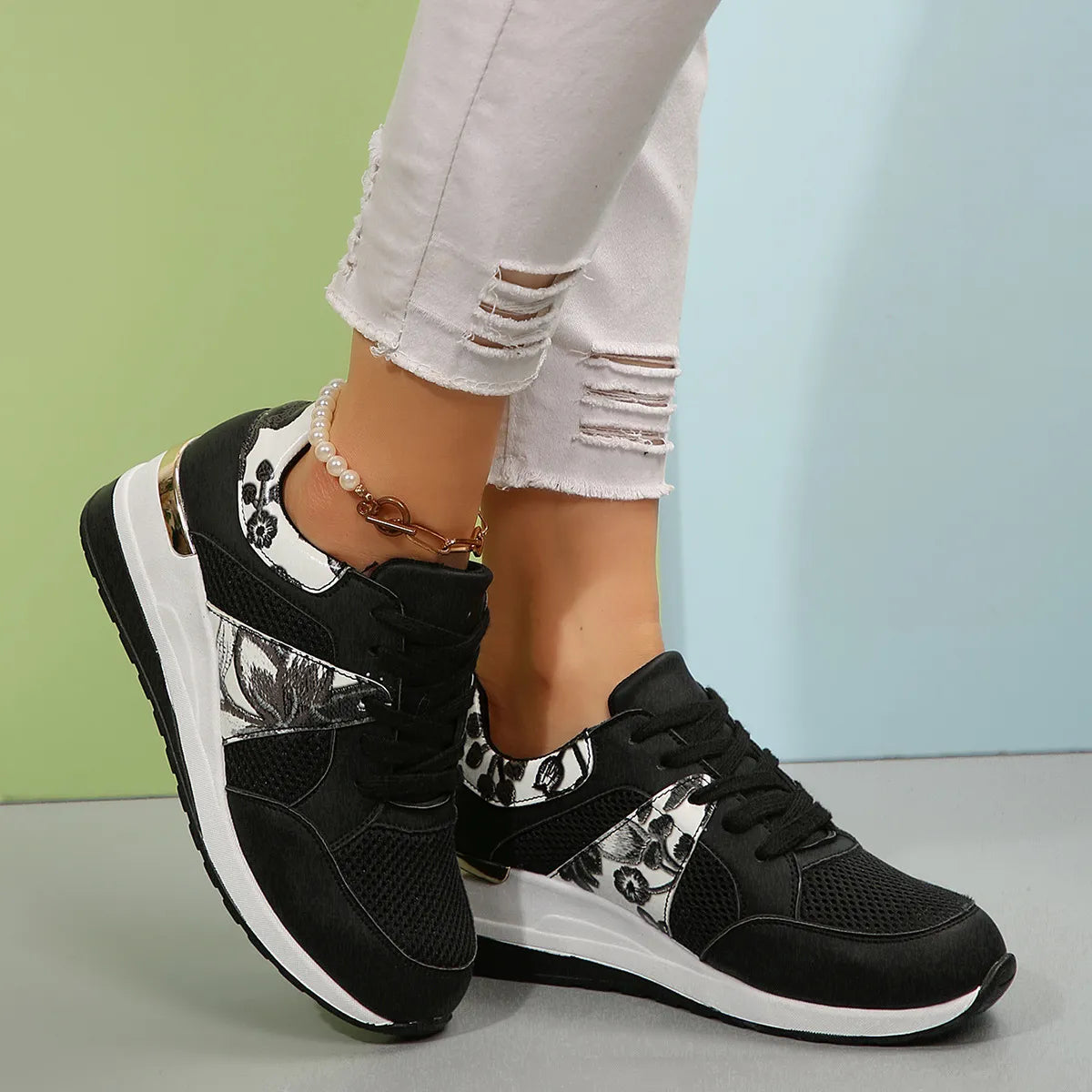 Black sneakers with black-and-white floral side panels worn on feet