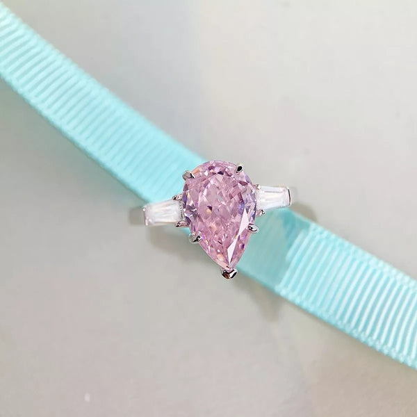 Two silver-tone teardrop rings shown with yellow and pink center stones.