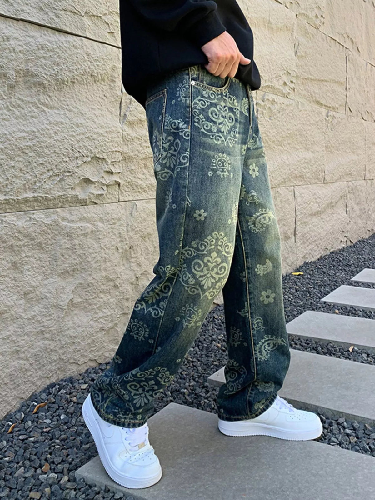 Side view of loose blue jeans showing an all-over pale scroll and floral pattern