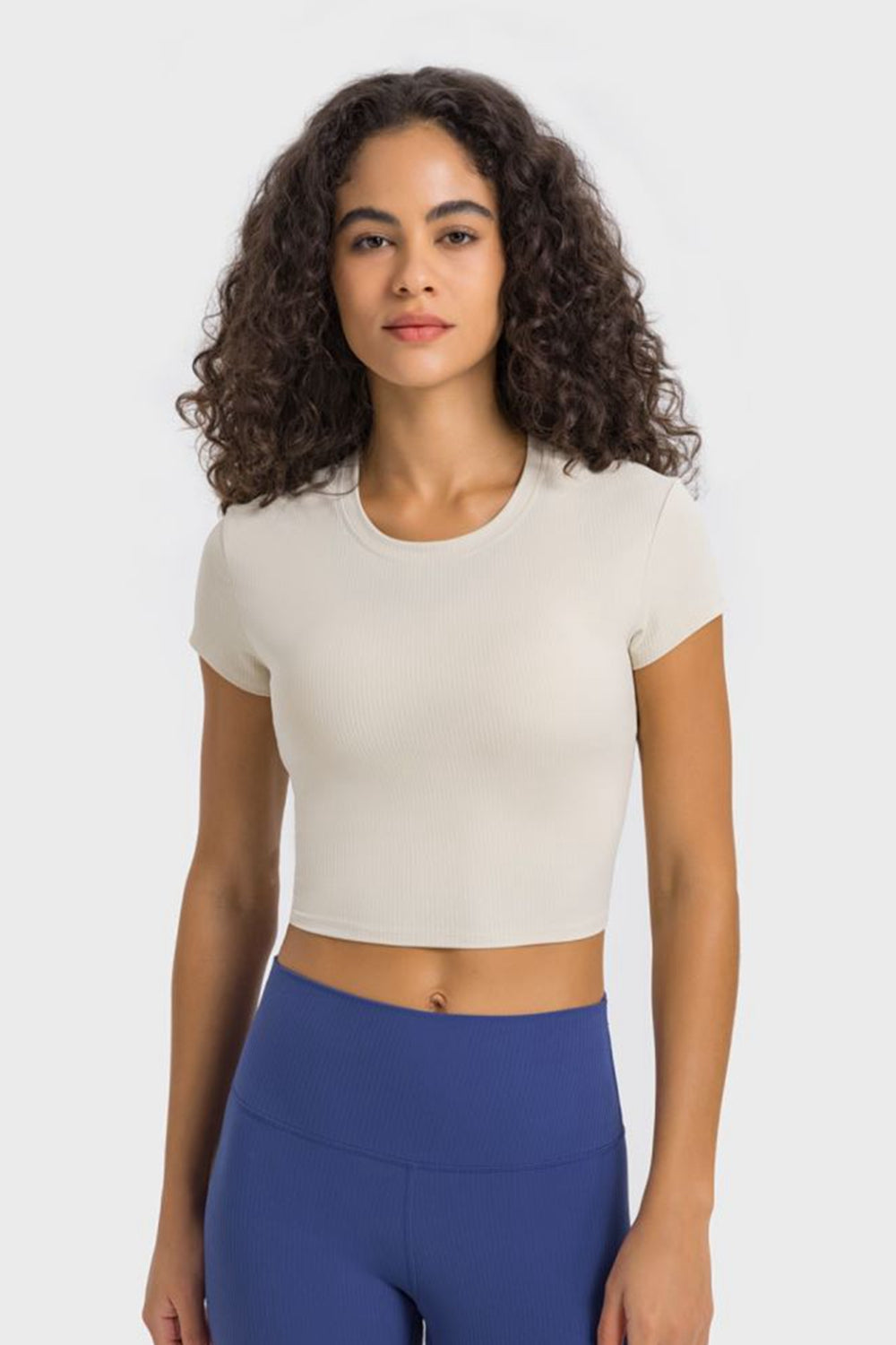 Model wearing an ivory cropped T-shirt with blue leggings, front view