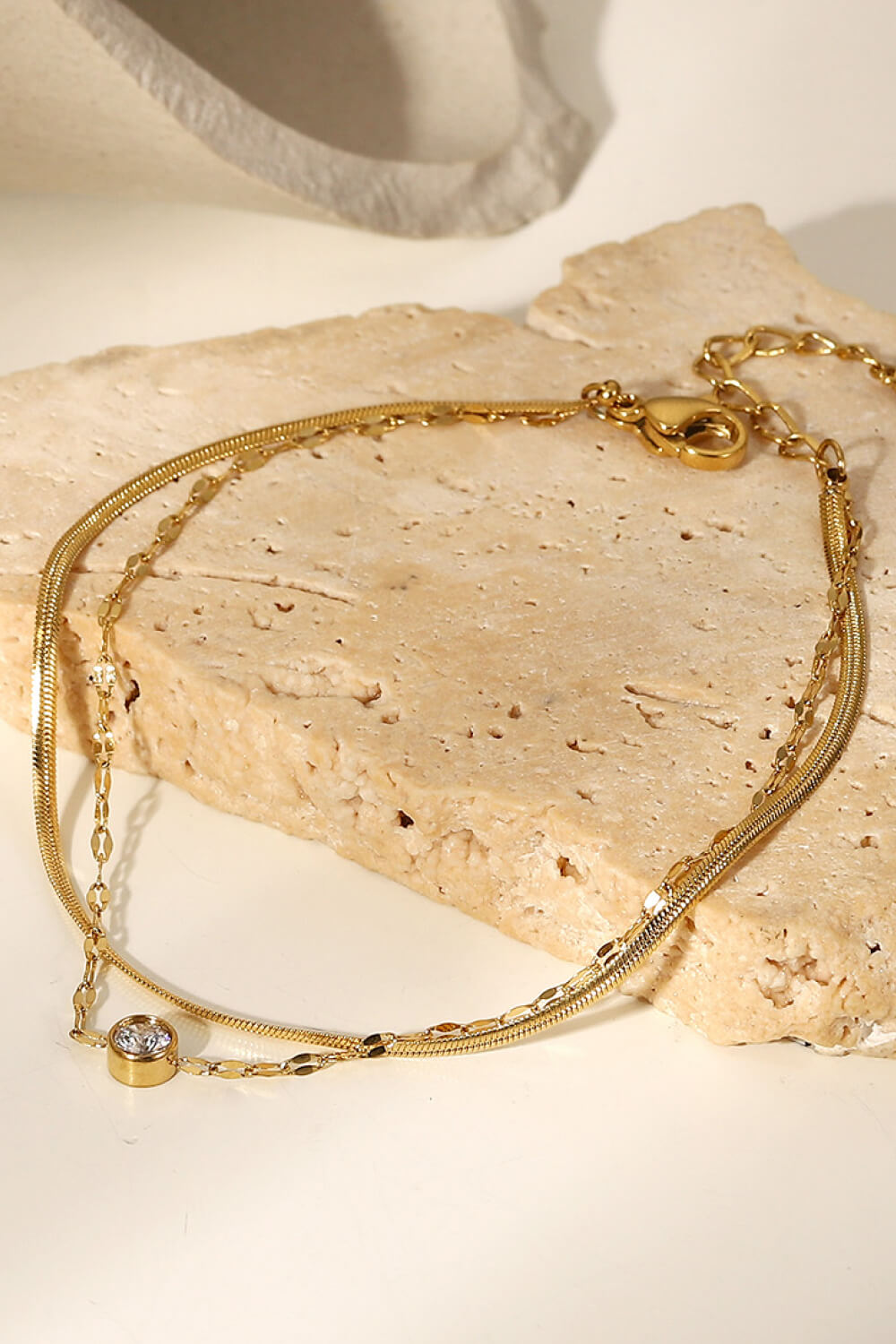 Gold-plated double-layer bracelet displayed on a light surface