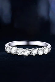 Silver-tone ring with round clear stones on a dark background