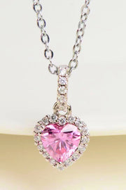 Pink heart-cut moissanite pendant with halo displayed on a tabletop