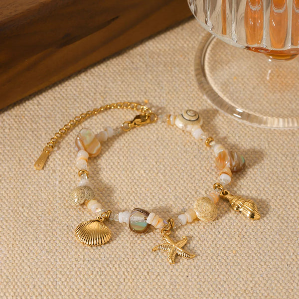 Gold shell charm bracelet displayed on a neutral surface