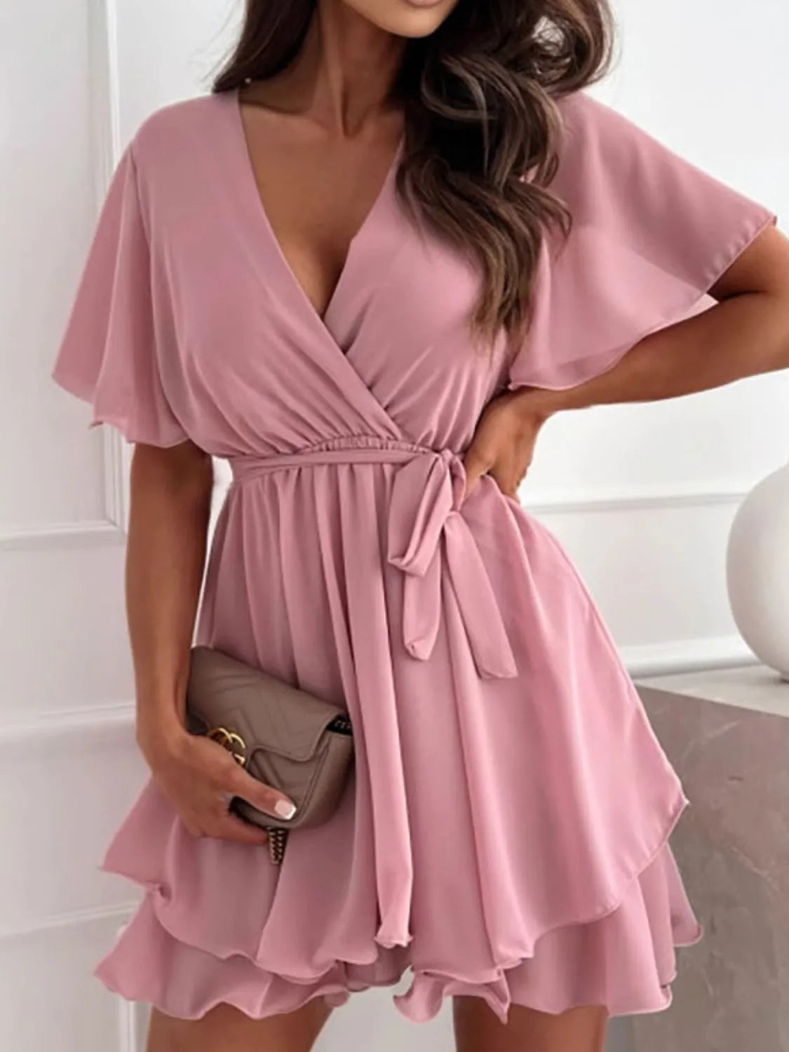 Close view of dusty pink flutter sleeves and layered ruffle skirt