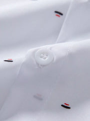 Close-up of white shirt fabric showing a button and small red and black printed motifs