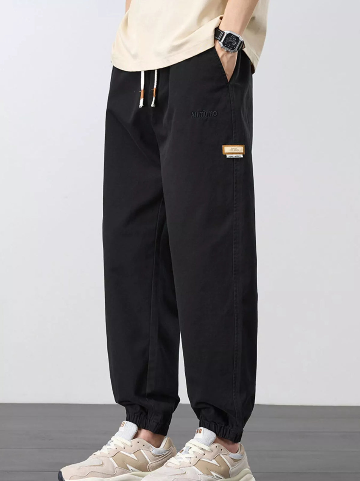 Angled front view of black joggers showing the side pocket and drawstring waist.