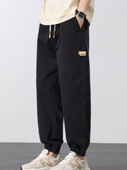 Angled front view of black joggers showing the side pocket and drawstring waist.