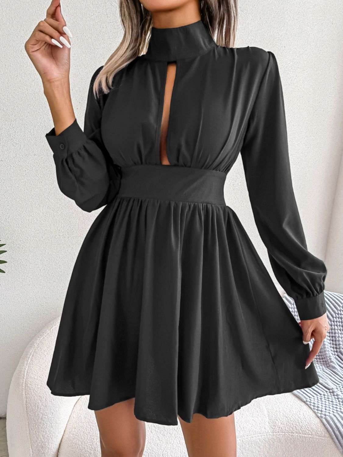 Model turns in the black cutout turtleneck mini dress