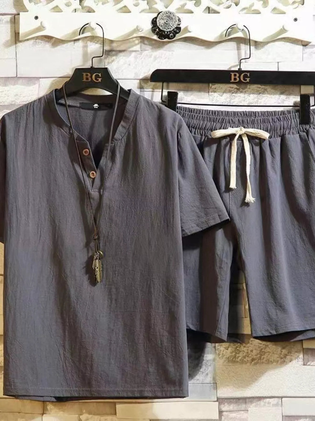Gray short-sleeve button-front shirt and matching drawstring shorts on hangers