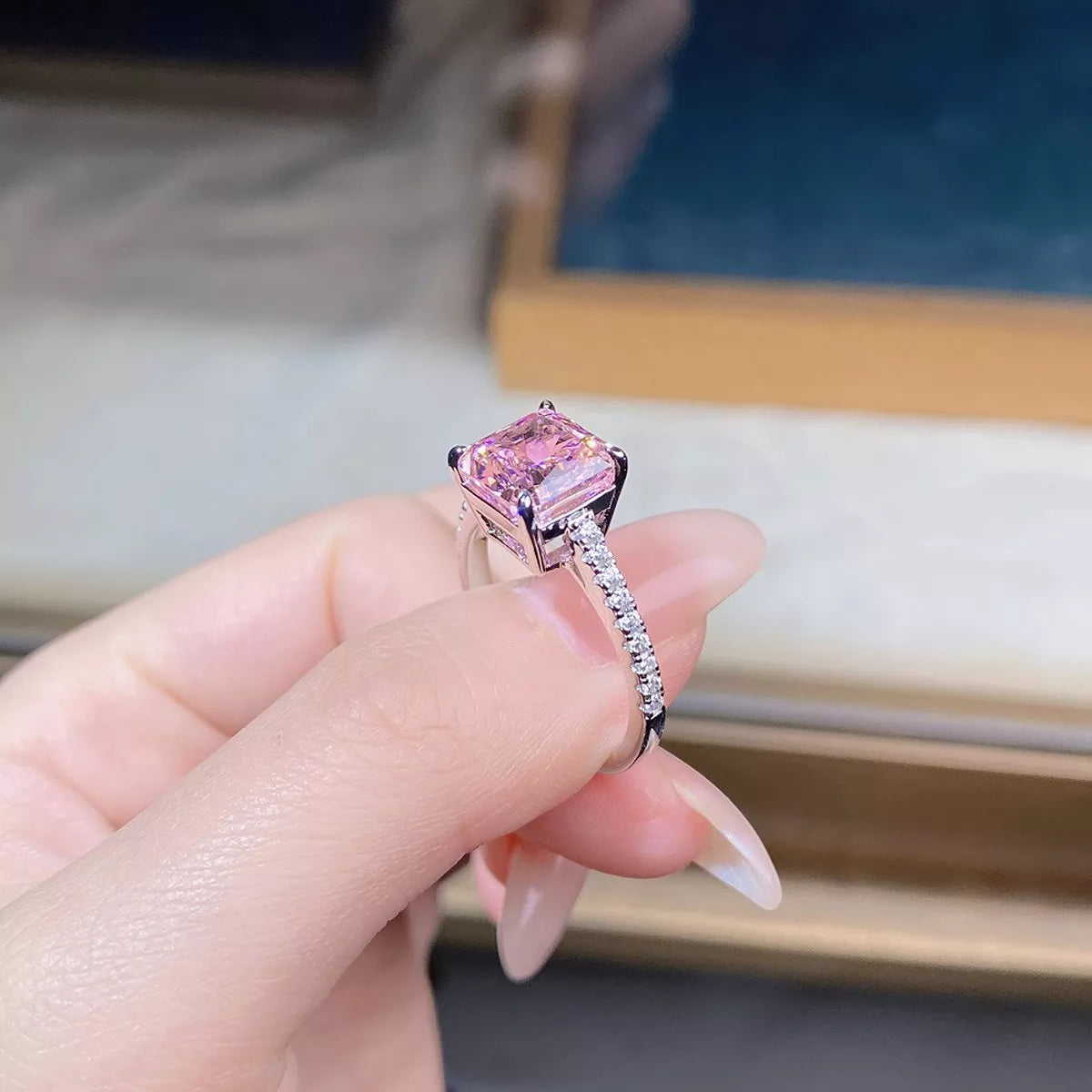 Ring held in hand to show the raised pink stone