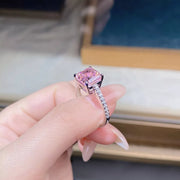 Ring held in hand to show the raised pink stone