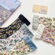 Close-up of sheer floral socks with dark, gray, blue and cream cuffs