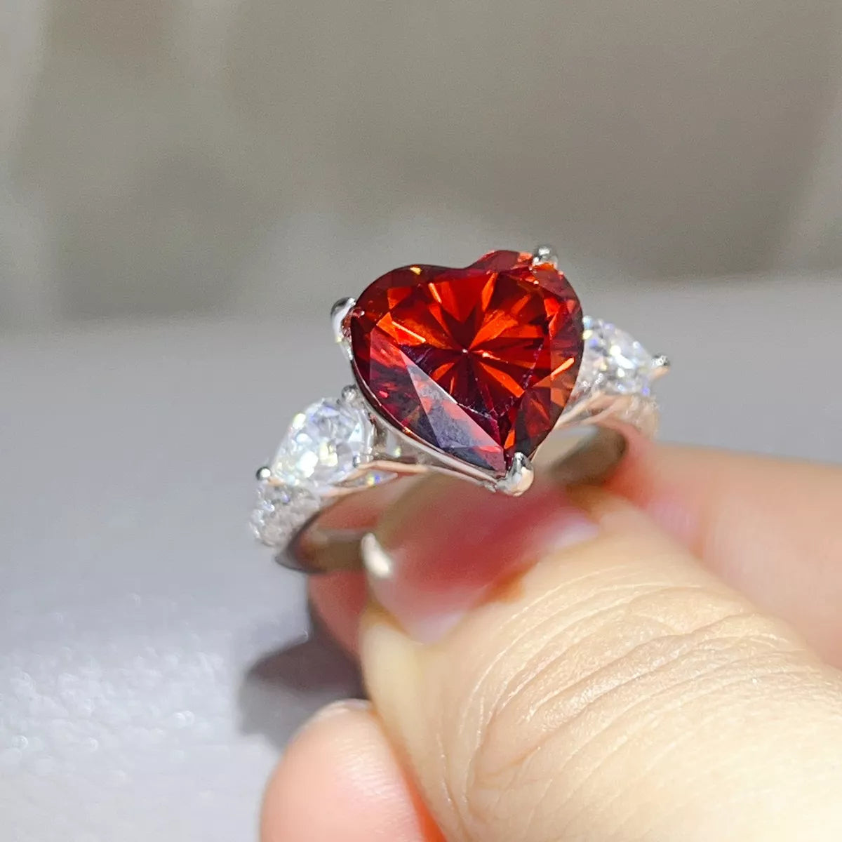 Close view of the heart-shaped red centre stone and raised silver setting.