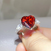 Close view of the heart-shaped red centre stone and raised silver setting.