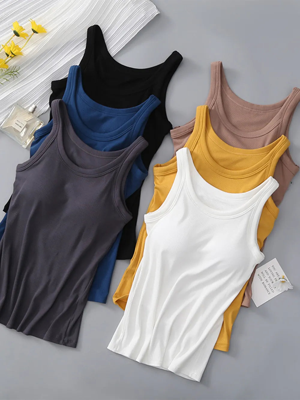 Five viscose tank tops in dark grey, black, dark blue, mustard and taupe, arranged flat