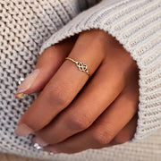 Close-up of the gold infinity-heart ring worn on a hand