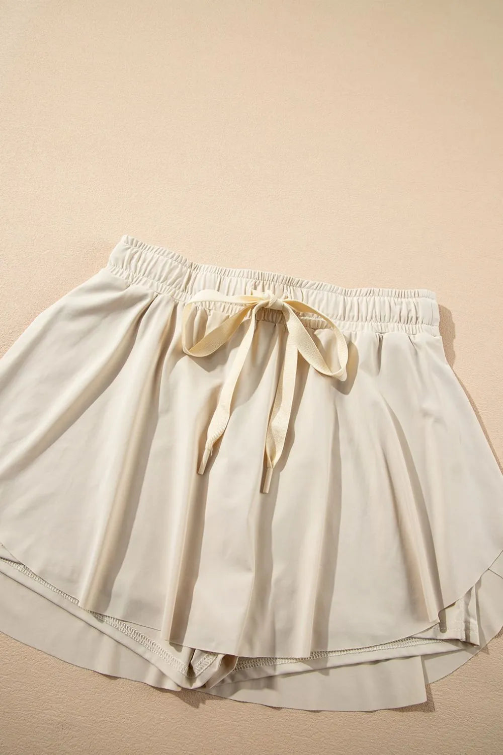 Ivory skort laid flat with front tie and elastic waistband.