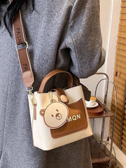 Ivory and brown bucket crossbody bag shown from the side with detachable strap