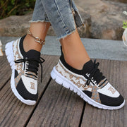 Black and white mesh lace-up sneaker with tan geometric panels, worn outdoors