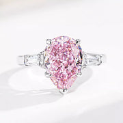 Close-up of a pink teardrop center stone flanked by clear baguette-shaped stones.