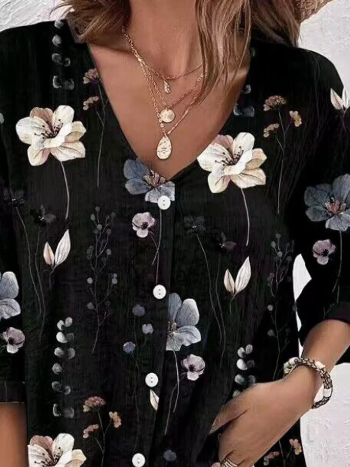 Close-up of black floral blouse with V-neck and button placket.