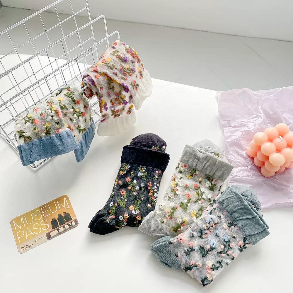Five floral sheer socks arranged on a wire rack and tabletop