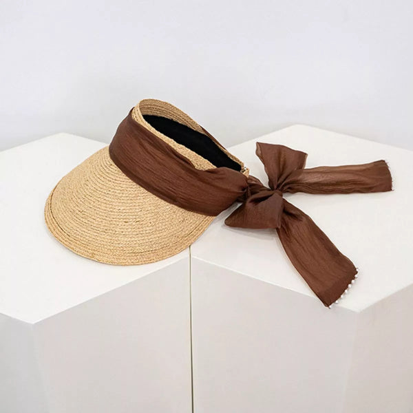 Straw visor sun hat with coffee-brown ribbon tied in a bow, angled view