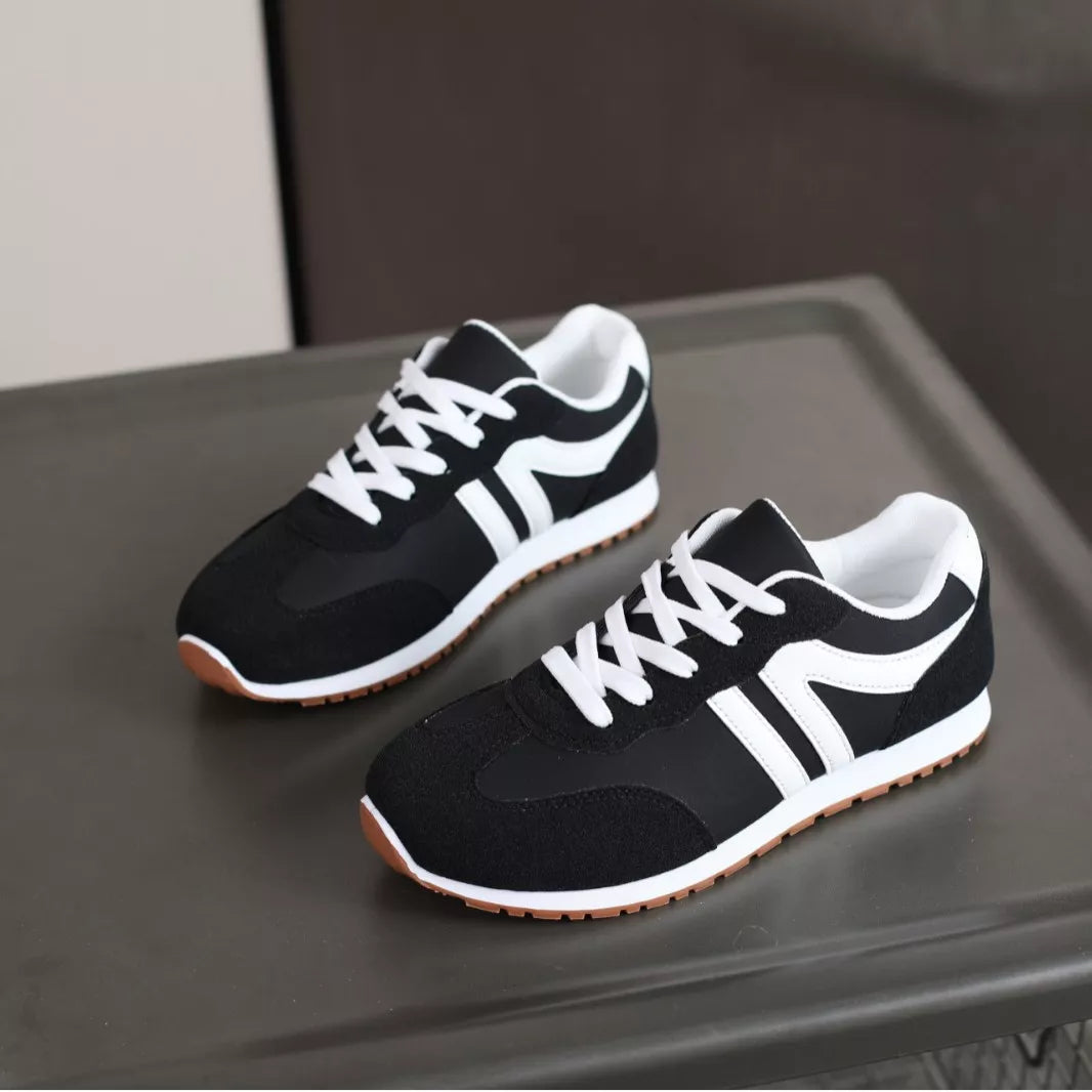 Pair of black sneakers with bold white side stripes