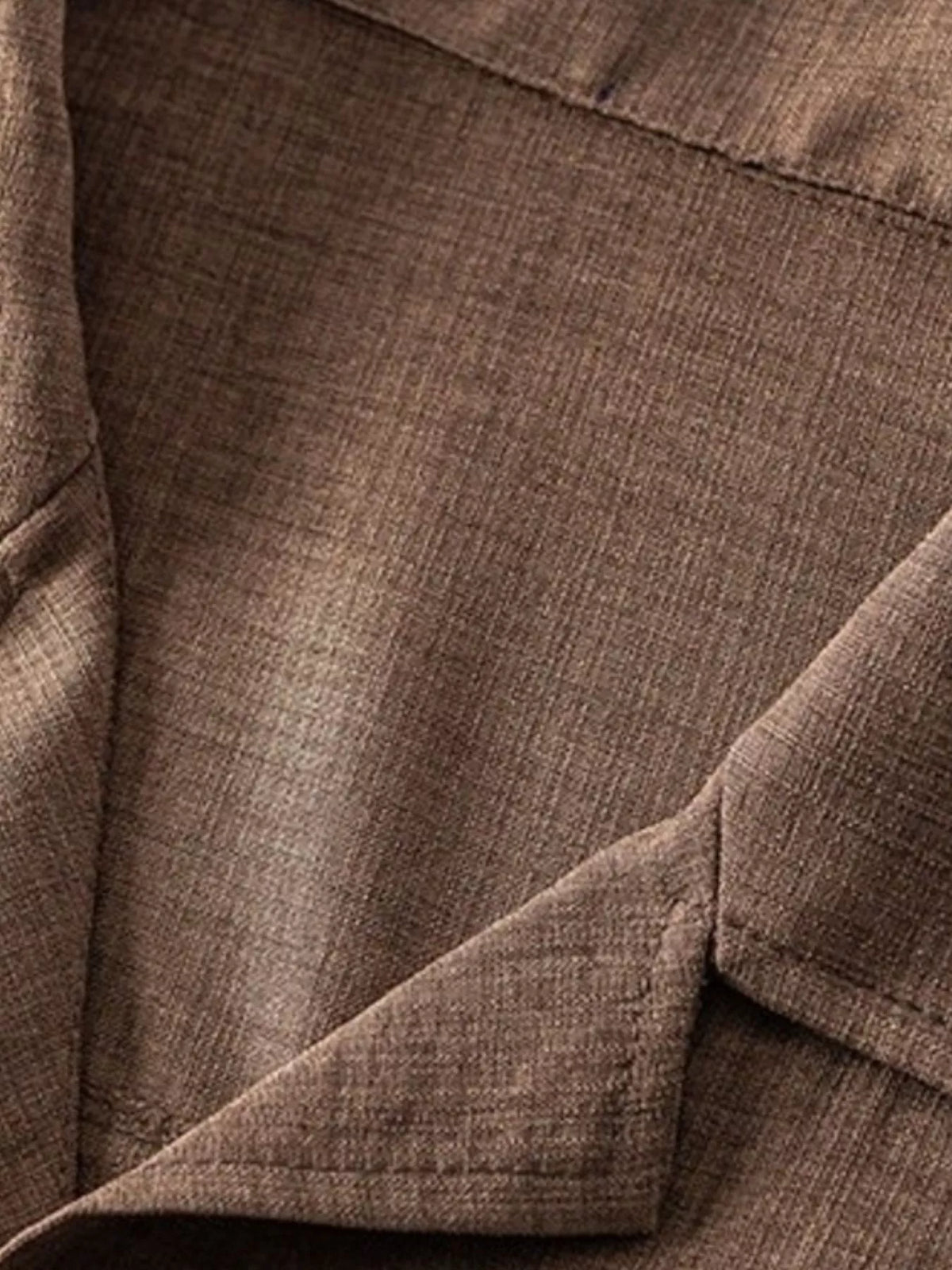 Close-up of the brown shirt fabric and chest pocket.