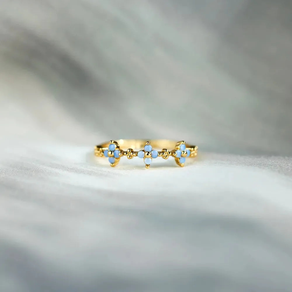 Side view of the blue-stone flower ring on a light surface
