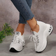 White lace-up platform sneakers worn with blue jeans, front angled view