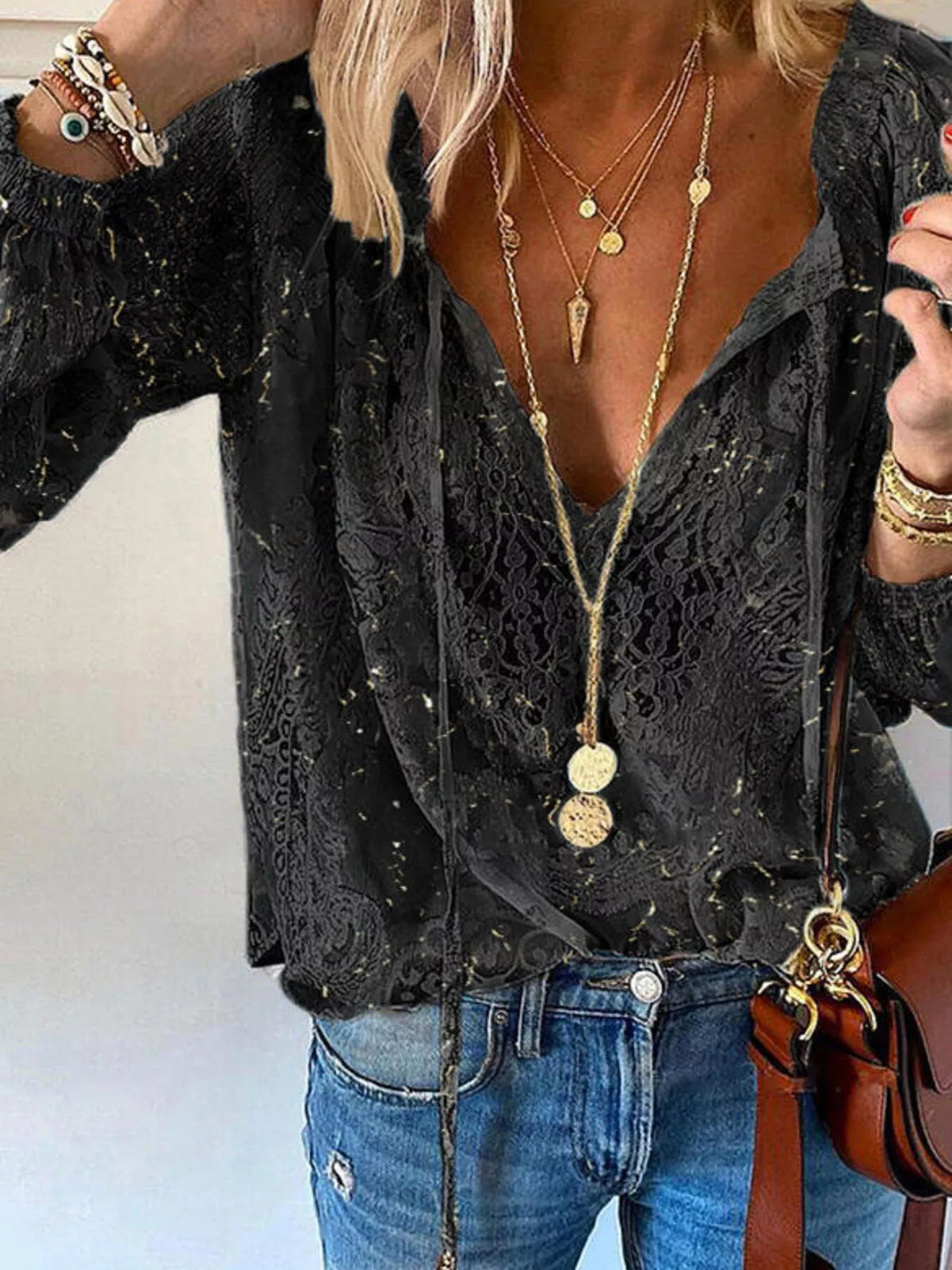 Black lace blouse styled with blue jeans, front view of tied neckline