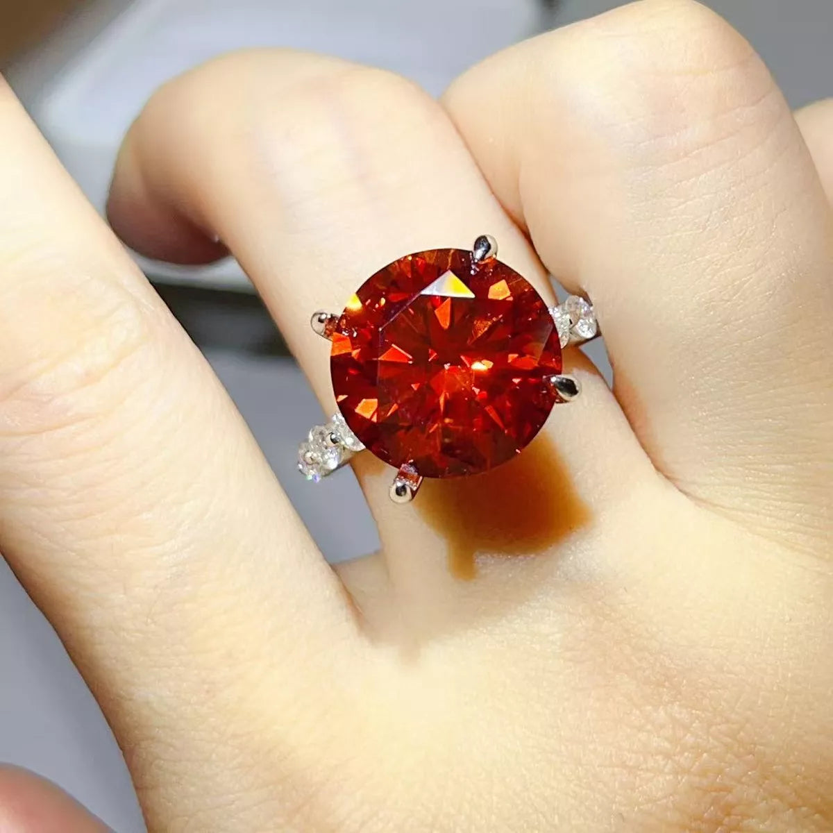 Side view of orange-red round-stone ring and silver setting