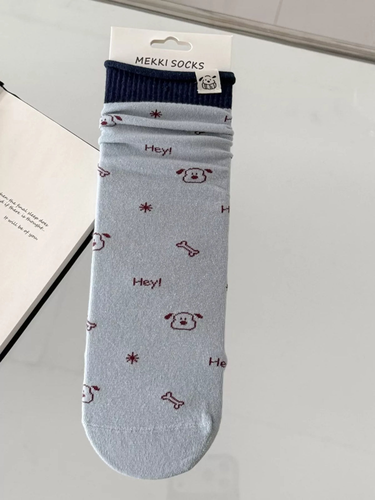 Light blue sock with small cartoon motifs shown flat