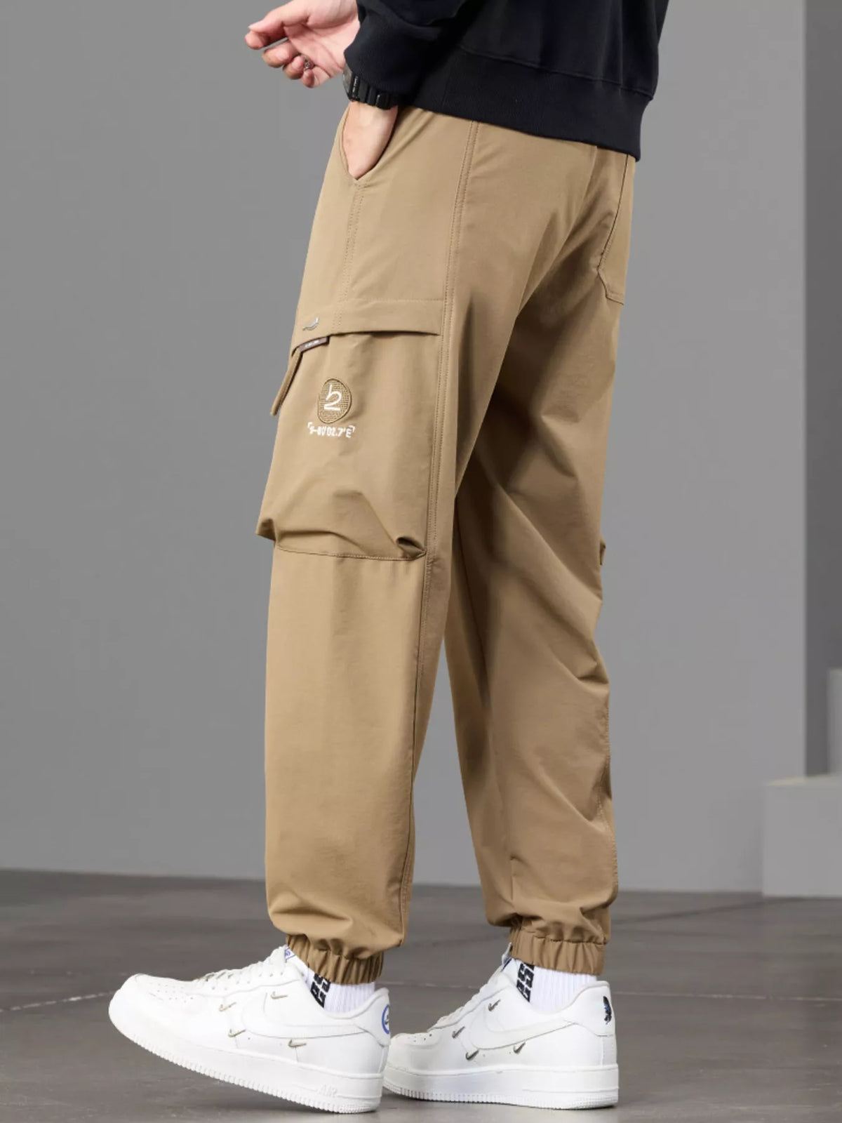 Angled side view of tan cargo joggers with flap pocket and gathered ankle cuffs.