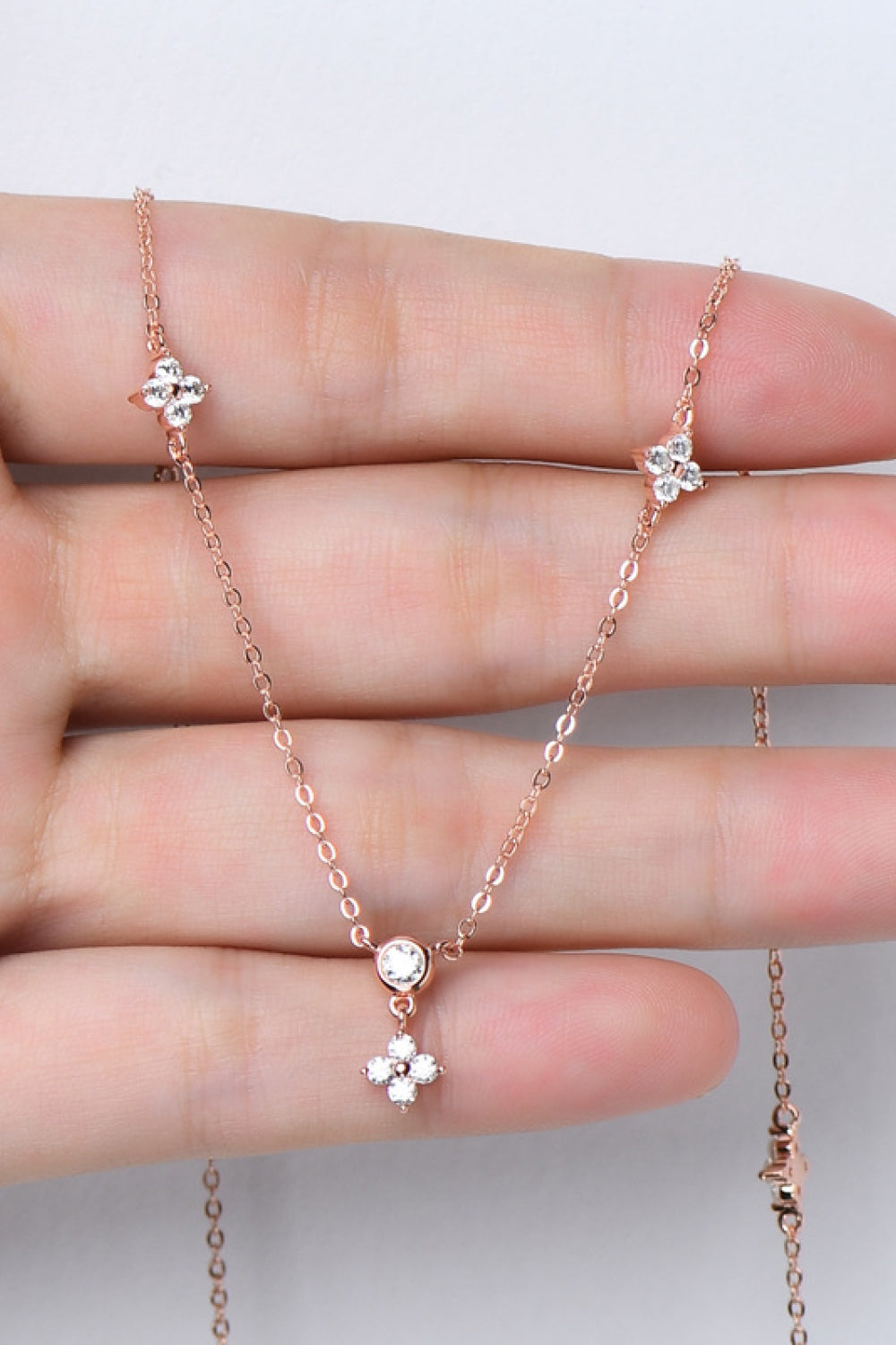 Delicate silver-tone necklace with small stones draped across a hand