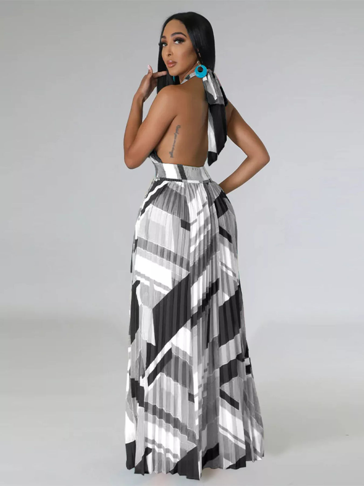 Three-quarter back view of a black-and-white halter maxi dress showing the open back.