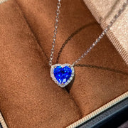 Close view of blue heart-shaped zircon pendant edged with clear stones on silver chain