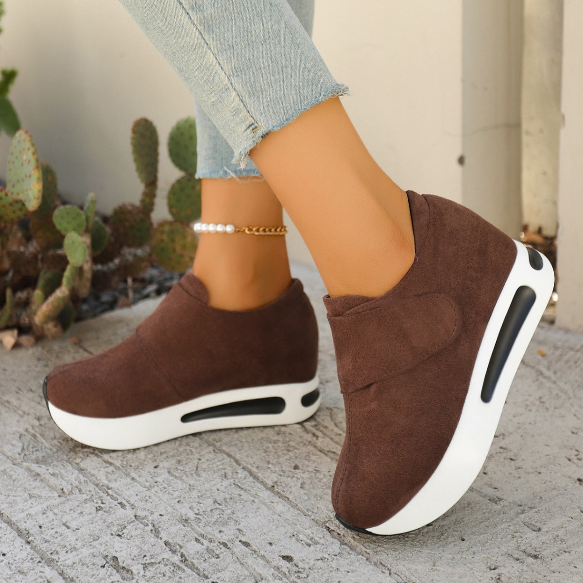 Brown slip-on platform sneakers with thick white soles worn with jeans