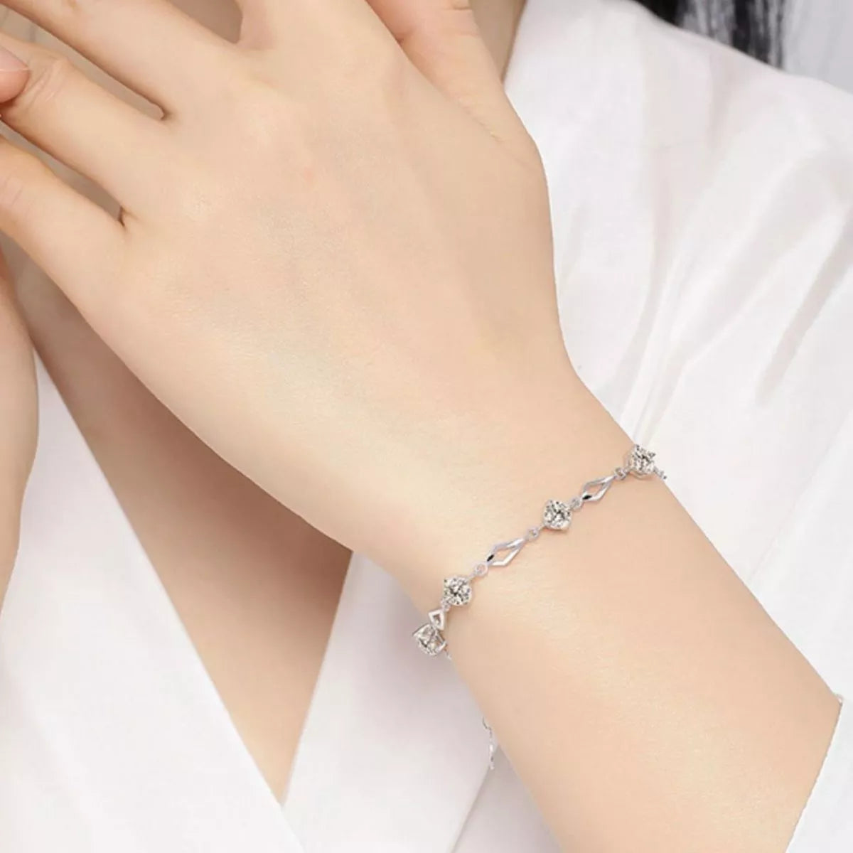 Silver wavy-link bracelet with floral zircon accents shown on the back of a hand