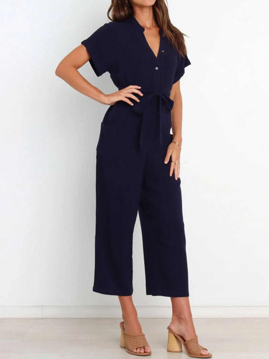 Women's navy notched-neck jumpsuit, front view with one hand on hip
