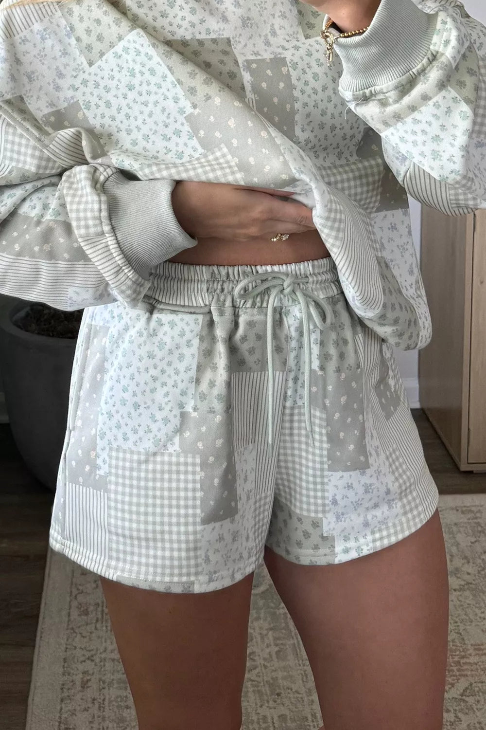 Close-up of sage gray patchwork shorts with elastic drawstring waist and matching pullover