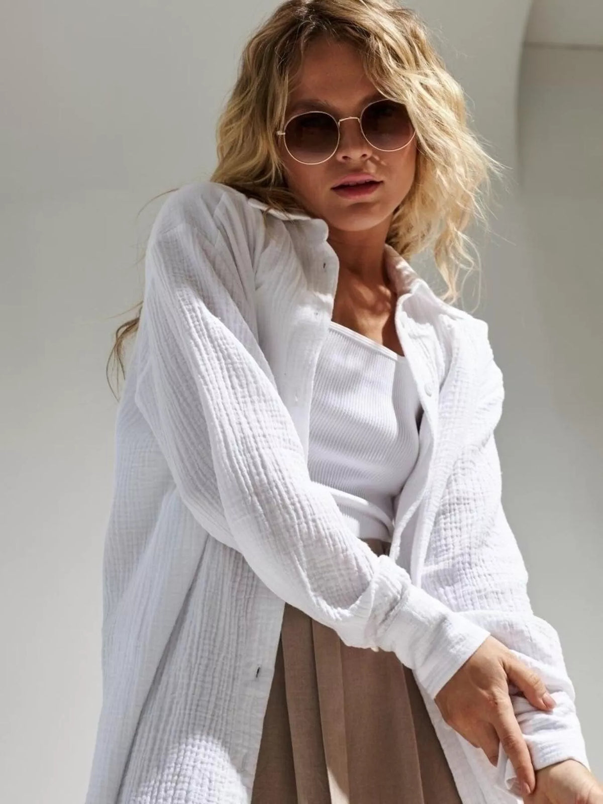 Model wearing a white textured gauze button-down shirt over a tank top.