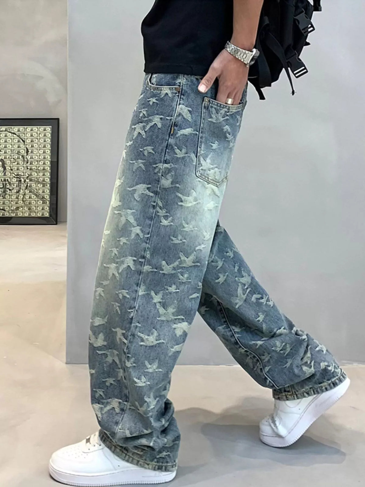 Rear angled view of blue bird-print jeans showing a patch pocket